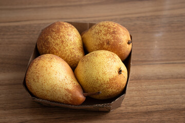 Wall Mural - Close up of ripe organic pear fruits in a paper box on kitchen table 