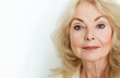 © muhammadarslan - A beautiful, elegant, and gorgeous mature woman in her fifties with white hair gently touching the skin of her face, smiling at the camera for a skincare commercial. She is isolated on a light grey ba
