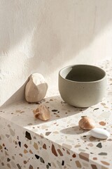 Poster - A terrazzo surface features soft tones of terracotta and olive green on a warm beige base, complemented by natural stones, creating a serene and inviting atmosphere in a contemporary setting