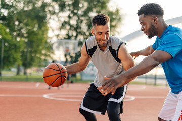 Two male basketball players defending during basketball match outdoors