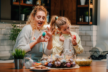 Wall Mural - Mother and daughter painting easter eggs in the kitchen