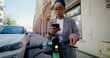 © m-art - A woman in formal clothes pays for a scooter rental from a mobile phone while standing on a city street. A sunny summer day