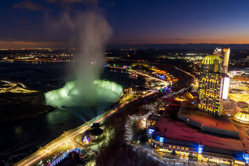 Wall Mural - Aerial view of Horseshoe Falls winter illumination in twilight time. Niagara Falls City downtown horizon. Stunning landscape dusk to night.