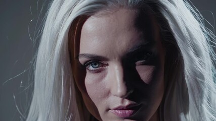 Aufkleber - A cinematic head-and-shoulders portrait with rich shadows, drawing attention to the striking contrast between her white hair and piercing blue gaze.