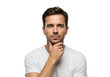 © Vooglo.com - A thoughtful man in a white t-shirt, resting his chin on one hand, isolated on a white background
