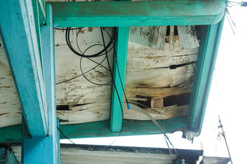Poster - Close-up of a teal-colored wooden structure showing significant signs of decay and wear. The wood is aged, weathered, and partially rotted. Decaying Teal Wooden Structure