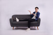 © NETI studio - Full body image of young Asian man posing on sofa on white background