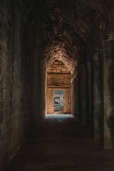 Wall Mural - Ancient stone corridor leading to a sunlit entrance.