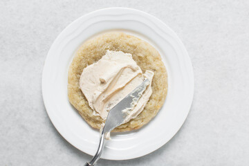 Wall Mural - Overhead view of vanilla frosting coated cookies, top view of vanilla cookies with a vanilla cream frosting, process of making bakery style cookies