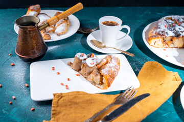 Wall Mural - Banana dessert Tarte tatin and croissants on a dark green background with a cup of coffee brewed in a cezve and freeze-dried raspberries.