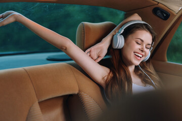 Wall Mural - Happy young woman listening to music in a car, enjoying her road trip with headphones, showcasing joy and relaxation in a vibrant green background.