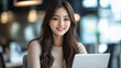 © Daniil - Young Asian woman working on laptop in modern office environment, focused on task and smiling brightly