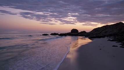 Poster - Sunset at a serene beach with gentle waves and rocky formations captured in tranquil evening light