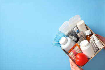 Wall Mural - Medical supplies box with various items including pills, bottles, bandages, and a heart-shaped object on a blue background. Ideal for healthcare, first aid, and medical themes