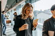 © Maskot - Smiling businesswoman holding coffee cup and walking with male colleague at office