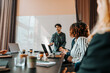 © Maskot - Young male entrepreneur brainstorming colleagues sitting in board room at office