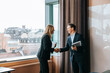 © Maskot - Happy male and female business professionals doing handshake at office
