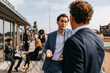 © Maskot - Businessman discussing with male colleague during coffee break in balcony