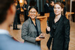© Maskot - Smiling female business professionals talking with delegate at convention center