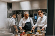 © Maskot - Female and male chef wearing uniform cooking food in kitchen at restaurant