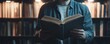 © STwul - Man reading book in library, bookshelves blurred background, education concept