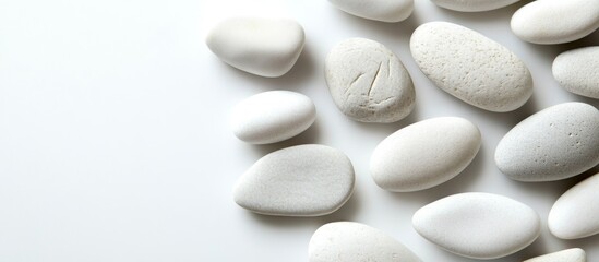 Poster - collection of smooth white pebbles arranged on a light background with ample copy space for text ove