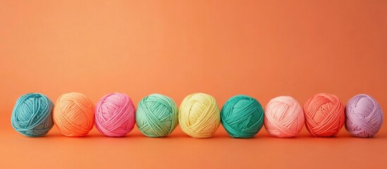 Poster - Colorful yarn balls arranged in a line on an orange background with copy space for text.
