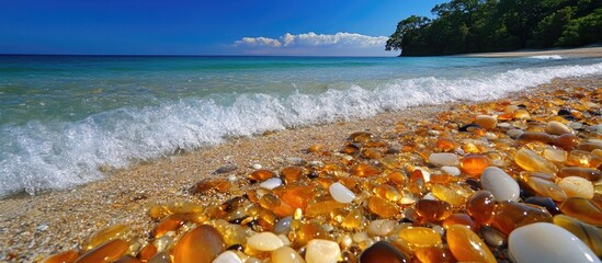 Poster - Beach with colorful pebbles and gentle waves under clear blue sky and green trees Copy Space