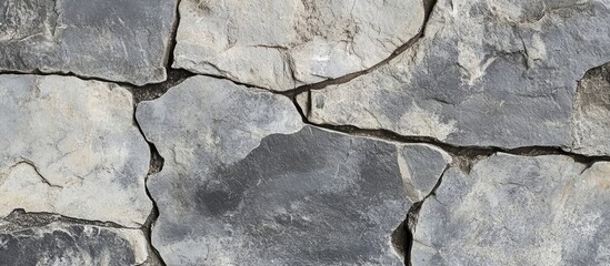 Poster - Textured surface of uneven gray stone wall with visible cracks and crevices suitable for background or architectural design use Copy Space