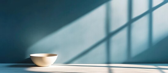 Poster - Minimalistic interior scene with empty white bowl on table and shadows from window on blue wall Copy Space
