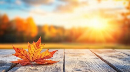 Poster - Autumn leaf on wooden table with blurred sunset background and warm colors Copy Space
