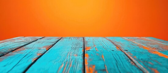Poster - Wooden tabletop with blue planks and vibrant orange background ideal for placing text or graphic elements Copy Space