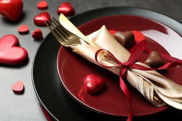 Wall Mural - Romantic place setting for Valentine's day. Tableware, cutlery and candies in shape of hearts on grey table, closeup