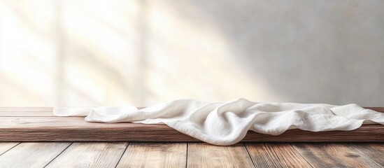 Poster - White cloth draped on a wooden surface with soft light and shadow patterns on a neutral wall background Copy Space