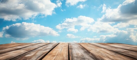 Poster - wooden tabletop with clouds and blue sky in the background showcasing natural light and space for te
