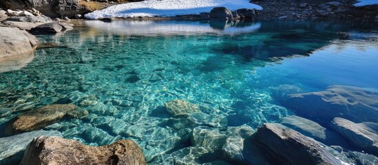 Aufkleber - Clear turquoise water in a natural lake with visible stones and snow on the shore under bright sunlight Copy Space