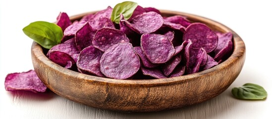 Aufkleber - Purple sweet potato chips in a wooden bowl garnished with basil leaves on a white background Copy Space