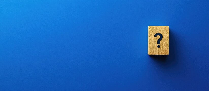 Wooden block with question mark symbol on blue background with copy space for text.