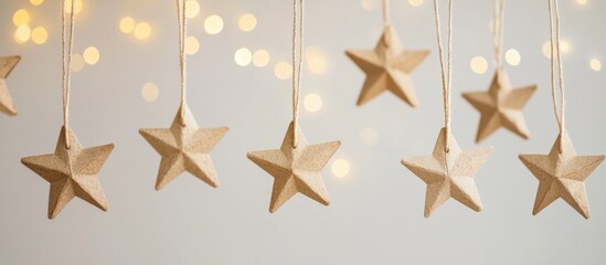 Poster - Hanging wooden stars with twine against a blurred background of soft glowing lights Copy Space