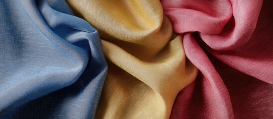 Poster - Colorful textured fabric background in blue yellow and pink shades with soft folds and wrinkles suitable for textile design Copy Space