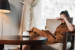 © SHOTPRIME STUDIO - A relaxed woman in a brown dress enjoying reading a book while sitting in a cozy living room with a cup of coffee, evoking comfort and tranquility