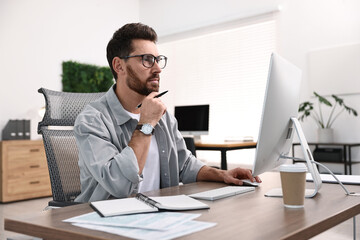 Wall Mural - Man working on computer at table in office