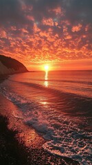 Poster - A breathtaking sunset illuminates the ocean with fiery shades of orange and pink as gentle waves lap against the sandy shore. Clouds dance above, creating a stunning backdrop