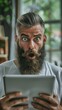 © COK House - A man with a beard looks at a tablet with a surprised expression on his face. Great for technology adverts, tutorials and marketing campaigns.