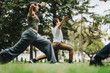 © qunica.com - A group of students practice yoga poses in a park setting with guidance from their instructor, enjoying the natural surroundings.