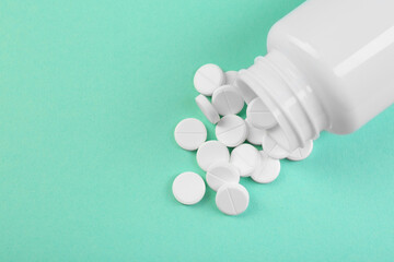 Wall Mural - Bottle of antibiotic pills on turquoise background, top view. Space for text