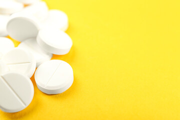 Wall Mural - Pile of antibiotic pills on yellow background, closeup. Space for text