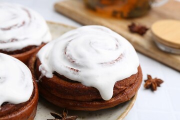 Tasty cinnamon rolls with cream and spices on white table, closeup