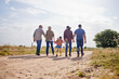 © peopleimages.com - Holding hands, family and walking with kid on farm for love, care or support with grandparents on dirt road. Back, mother and father with girl in countryside for travel, agriculture and generations