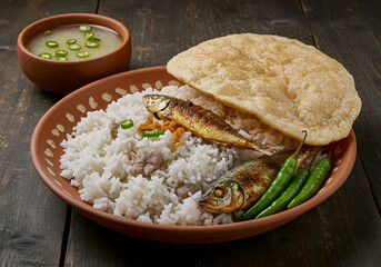 A traditional serving of Panta Bhat, a popular Bangladeshi rice dish served with fish and green chilies, ideal for Ramadan meals.